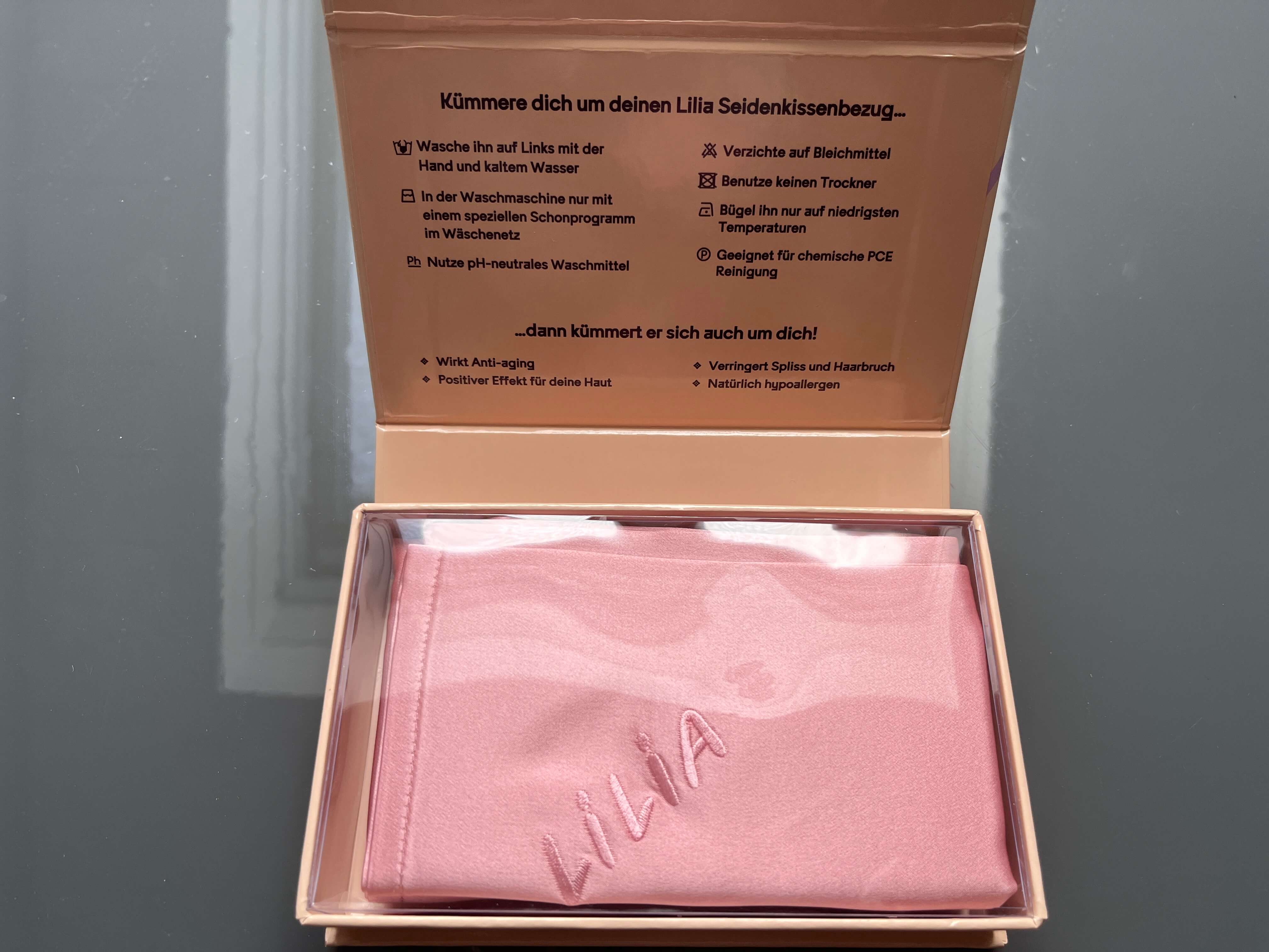 Caixa de cartão com fronha de seda rosa dobrada no interior